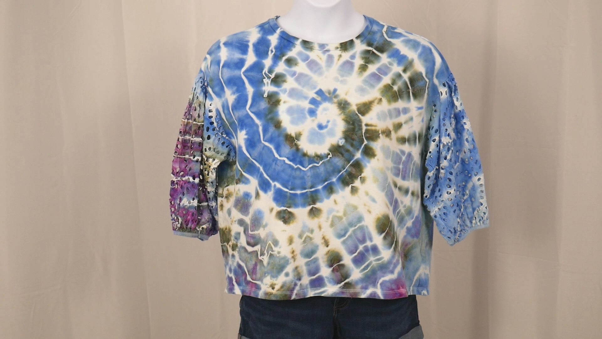 360 degree rotating view of hand dyed tie dye top size XXL showing blue green purple spiral pattern and eyelet lace sleeve detail