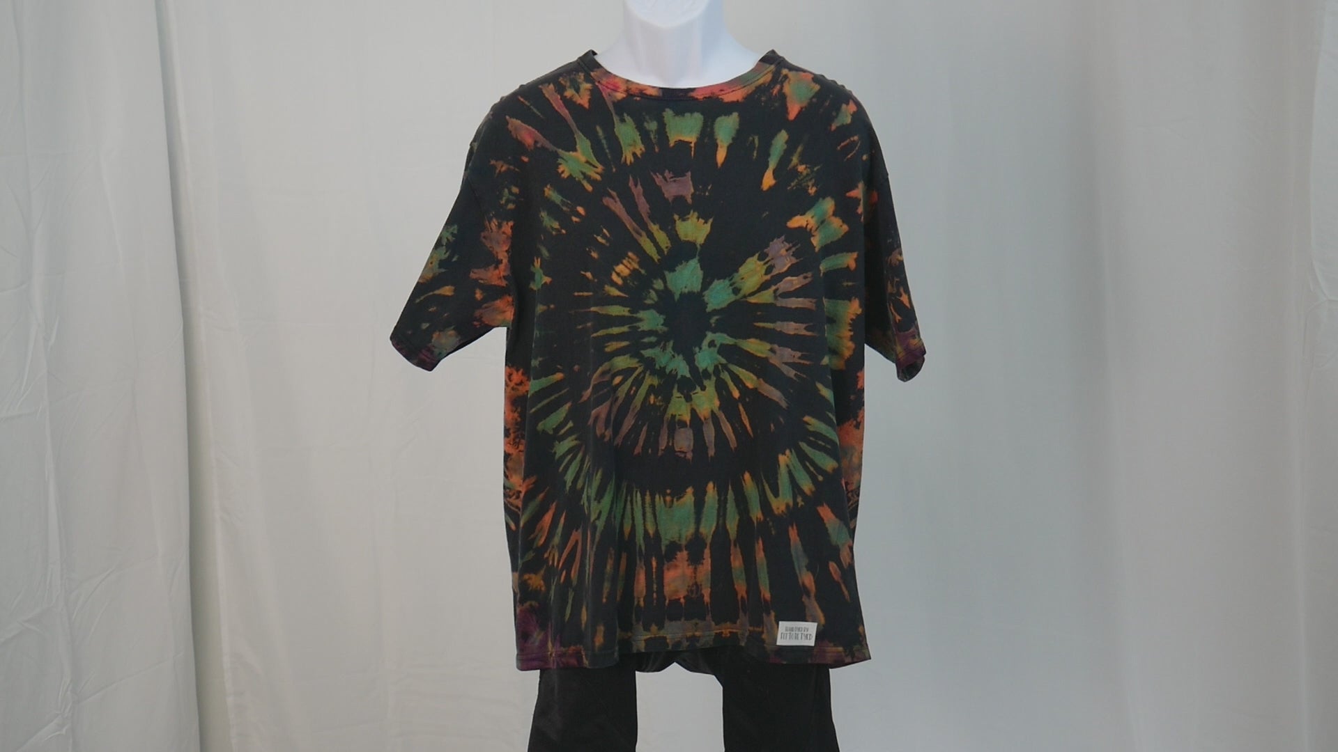 Ocular Reverse Tie Dye T Shirt using a Spiral Design in Green, Orange and Black, in size Large, video of shirt spinning
